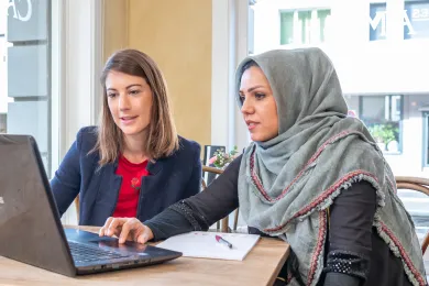 Eine JRK-Freiwillige hilft einer Frau am Computer