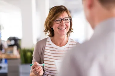 Eine Führungsperson utnerhält sich mit einer Person aus dem Team