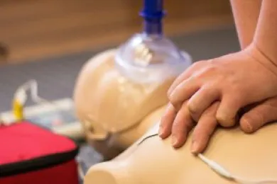 Eine Person übt die Reanimation an einer Puppe.