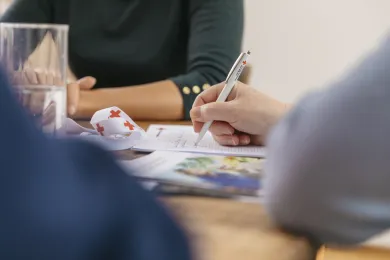 Jemand schreibt mit einem Stift etwas auf ein Papier.