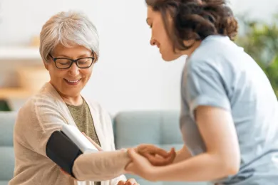 Eine Pflegeperson misst den Blutdruck einer Patientin