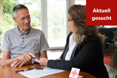 Eine Freiwillige erklärt einem Kunden den Rotkreuz-Notruf