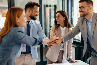 Ein Team streckt die Hände in der Mitte zusammen
