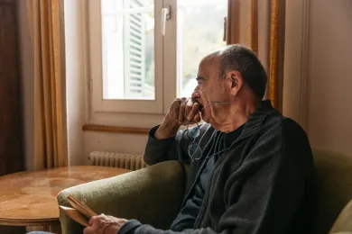 Älterer Mann schaut nachdenklich aus Fenster