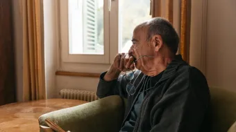 Älterer Mann schaut nachdenklich aus Fenster