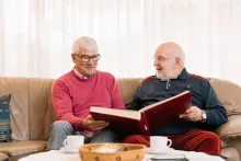 Ein Freiwilliger schaut sich zusammen mit einem älteren Herr ein Fotoalbum an.