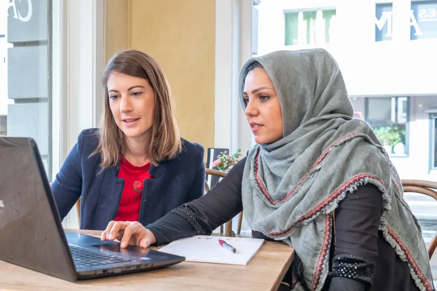 Eine JRK-Freiwillige hilft einer Frau am Computer