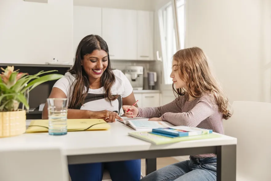 Eine JRK-Freiwillige hilf einem Mädchen mit den Hausaufgaben